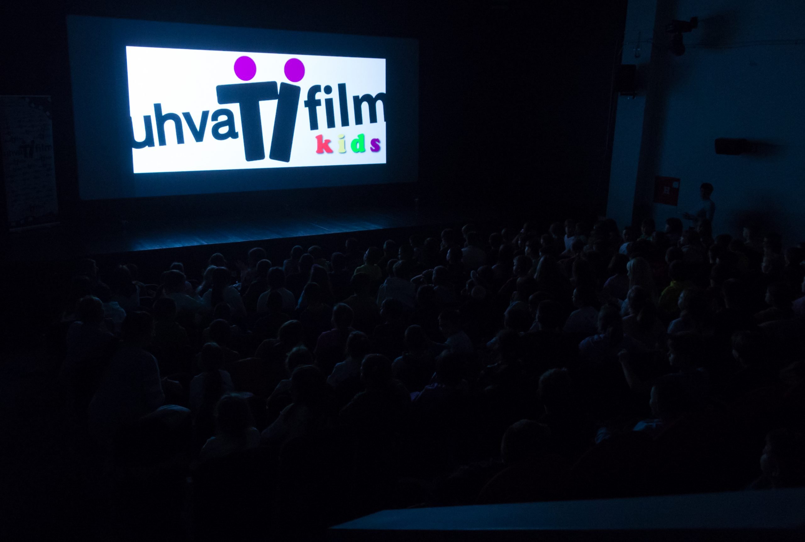 Bioskop Kultunog centra Futog. U mraku se vide obrisi publike u gledalištu. Na belom platnu je logo Uhvati film kids.